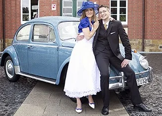Brautpaar vor einem taubenblauen VW Käfer als Hochzeitsauto