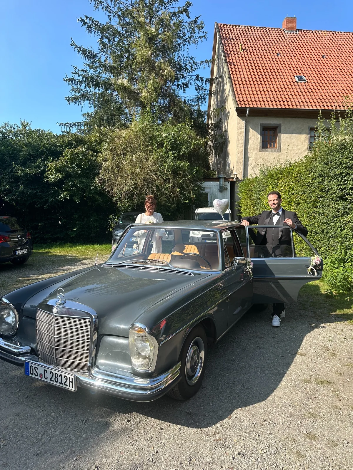 Brautpaar beim Aussteigen aus dem Mercedes-Benz W108 Hochzeitsauto