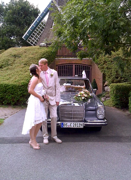 Brautpaar vor einem geschmückten Mercedes-Benz W108 Hochzeitsauto