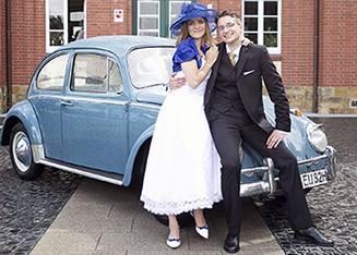 Brautpaar vor einem taubenblauen VW Käfer 1300 als Hochzeitsauto